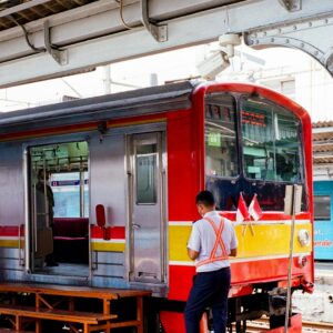 Man in safety vest on train platform beside an open train door.